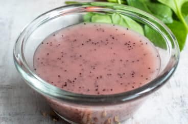 Poppyseed dressing in a clear bowl on a countertop.