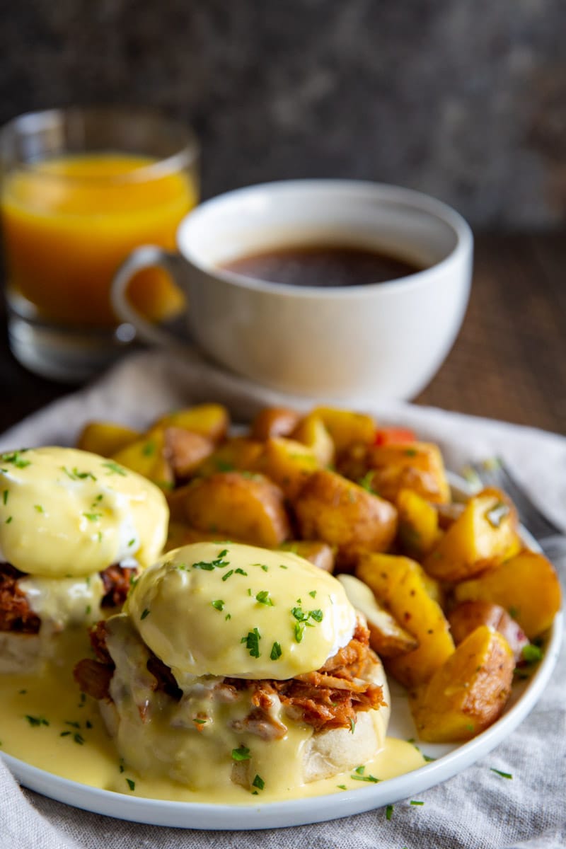 Pulled pork eggs benedict with a side of breakfast potatoes.