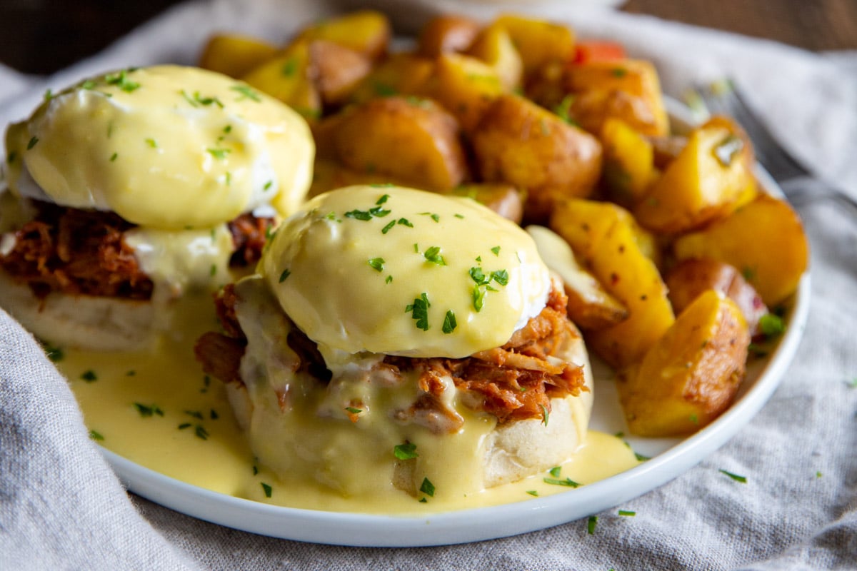 Pulled pork eggs benedict with a side of breakfast potatoes.