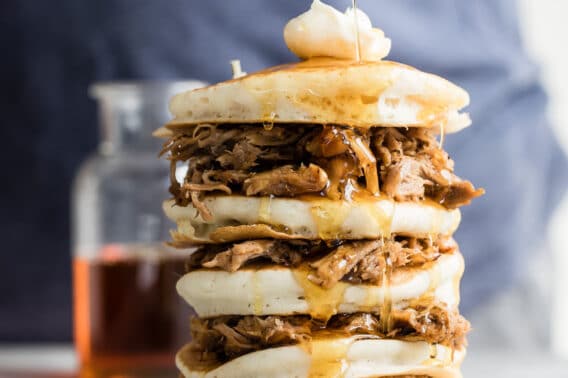 A stack of pulled pork pancakes with butter and whisky maple syrup on top.