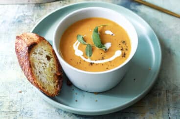 Two bowls of pumpkin soup with garnishes.