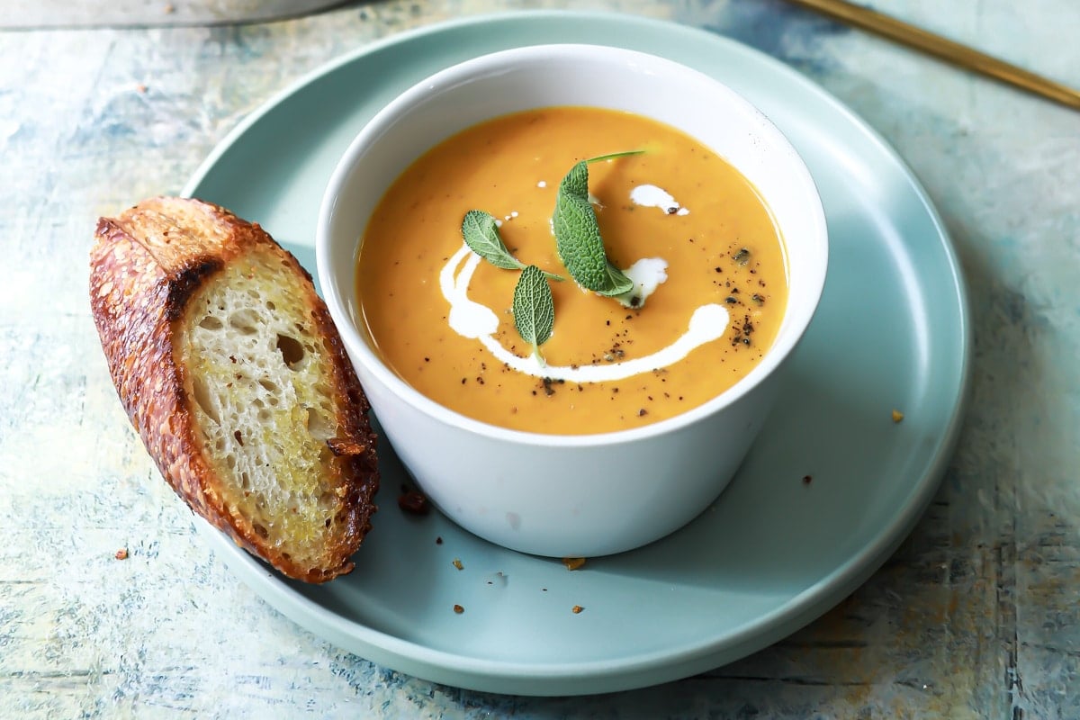 Two bowls of pumpkin soup with garnishes.