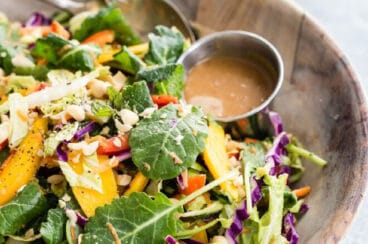 A bowl of rainbow thai mango salad with peanut dressing on the side.