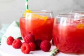 Glass of Raspberry Lemonade Fizz on a white board.