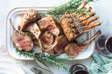 Roast rack of lamb on a white platter.