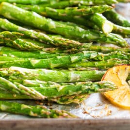 A baking sheet full of roasted asparagus with lemons.