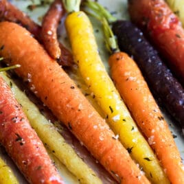 Roasted carrots on a parchment paper lined baking sheet.