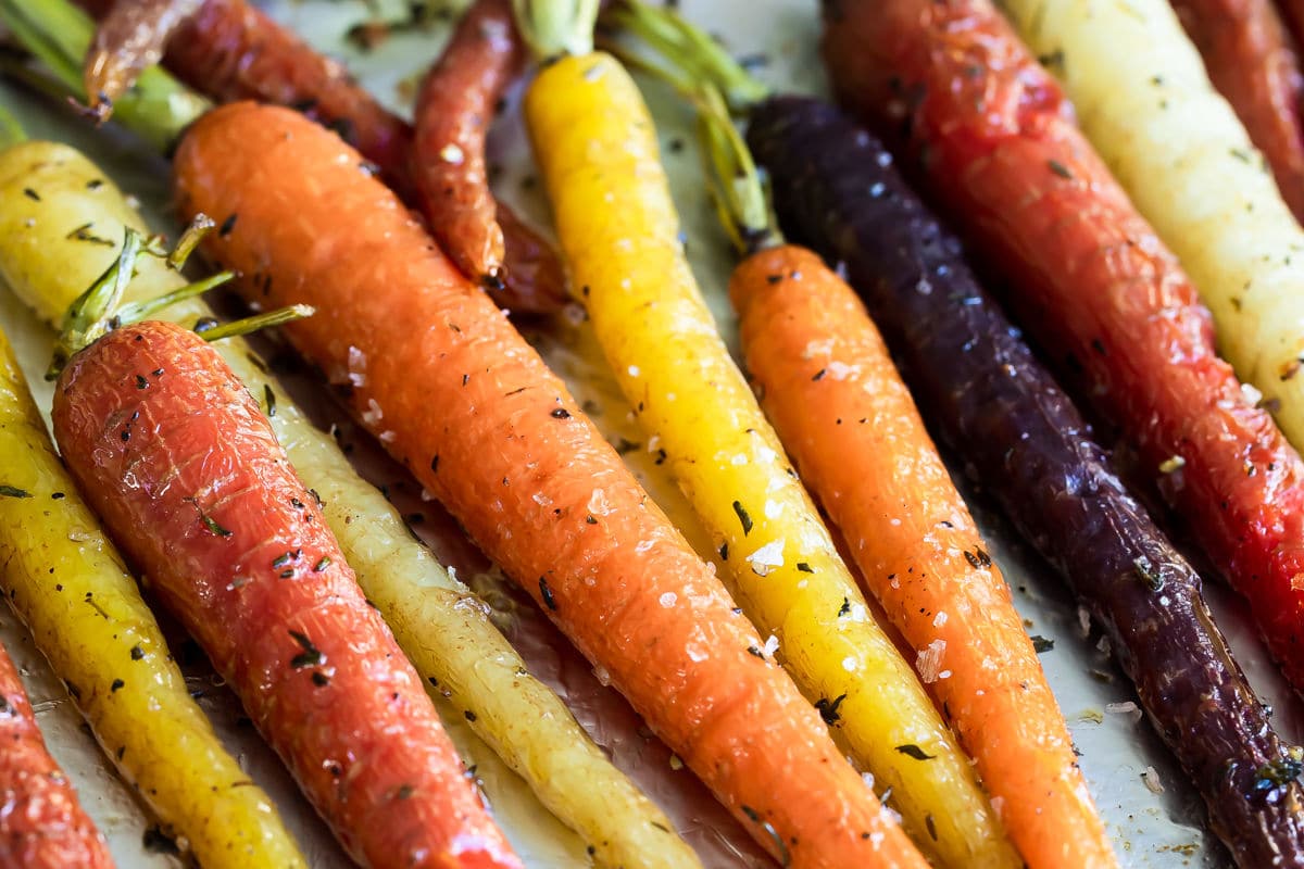 Roasted carrots on a parchment paper lined baking sheet.