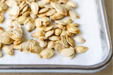 Roasted pumpkin seeds on a baking sheet.