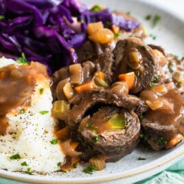 A plate with rouladen, braised red cabbage, and mashed potatoes.