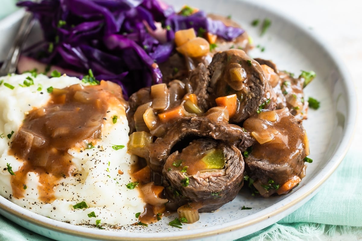 A plate with rouladen, braised red cabbage, and mashed potatoes.