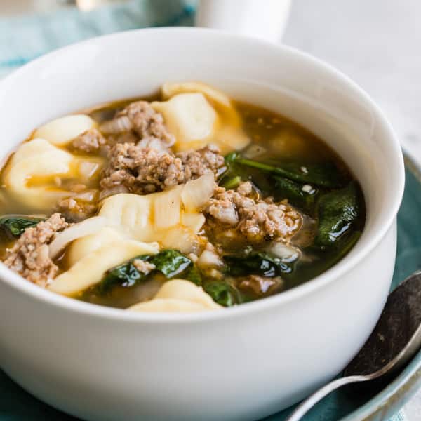 Sausage tortellini soup in a white bowl.
