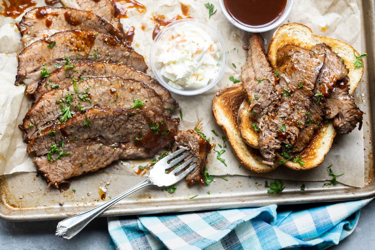 Slow cooker beef brisket slices on toast on a metal serving platter.