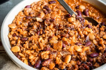 Slow cooker calico beans in a white serving dish.