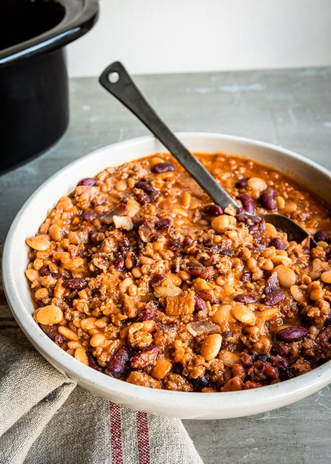 Slow cooker calico beans in a white serving dish.
