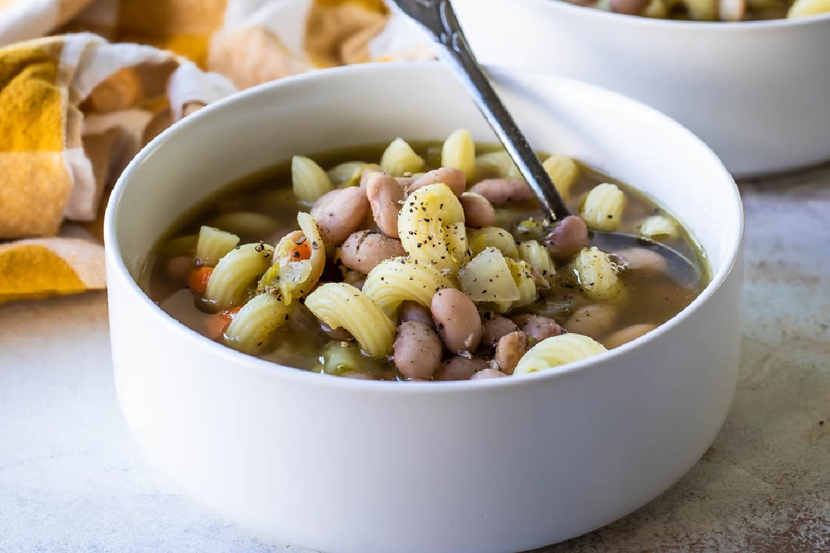 Slow cooker pasta and bean soup in a white bowl.