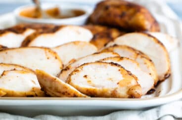 Smoked chicken breast slices on a white platter.