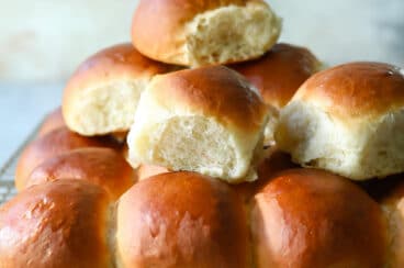 A cooling rack with soft yeast dinner rolls on it.