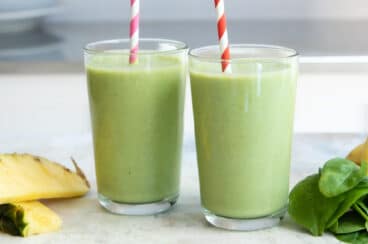 2 glasses of Spinach Smoothie with ingredients nearby.