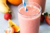 2 glasses with straws of Strawberry Citrus Ginger Smoothie next to fresh fruit.