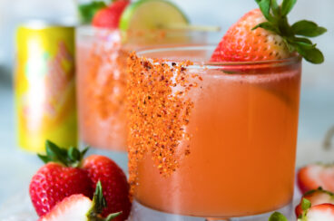 Two strawberry palomas surrounded by ice and strawberries.