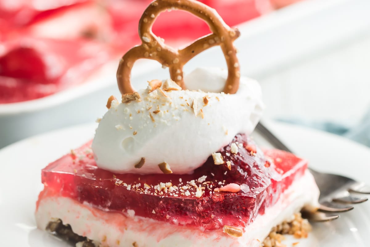 A serving of strawberry pretzel salad on a white plate with a fork.
