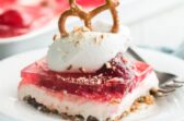 A serving of strawberry pretzel salad on a white plate with a fork.