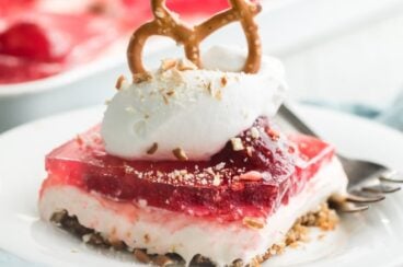 A serving of strawberry pretzel salad on a white plate with a fork.