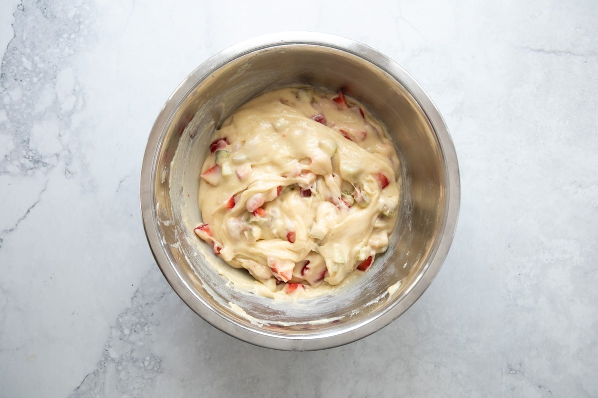 Strawberry rhubarb muffin batter in a silver mixing bowl.