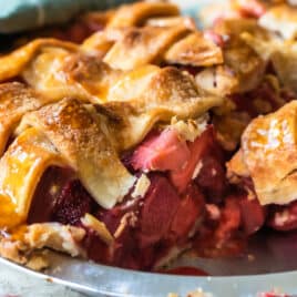A strawberry rhubarb pie in a pie pan with one slice removed.