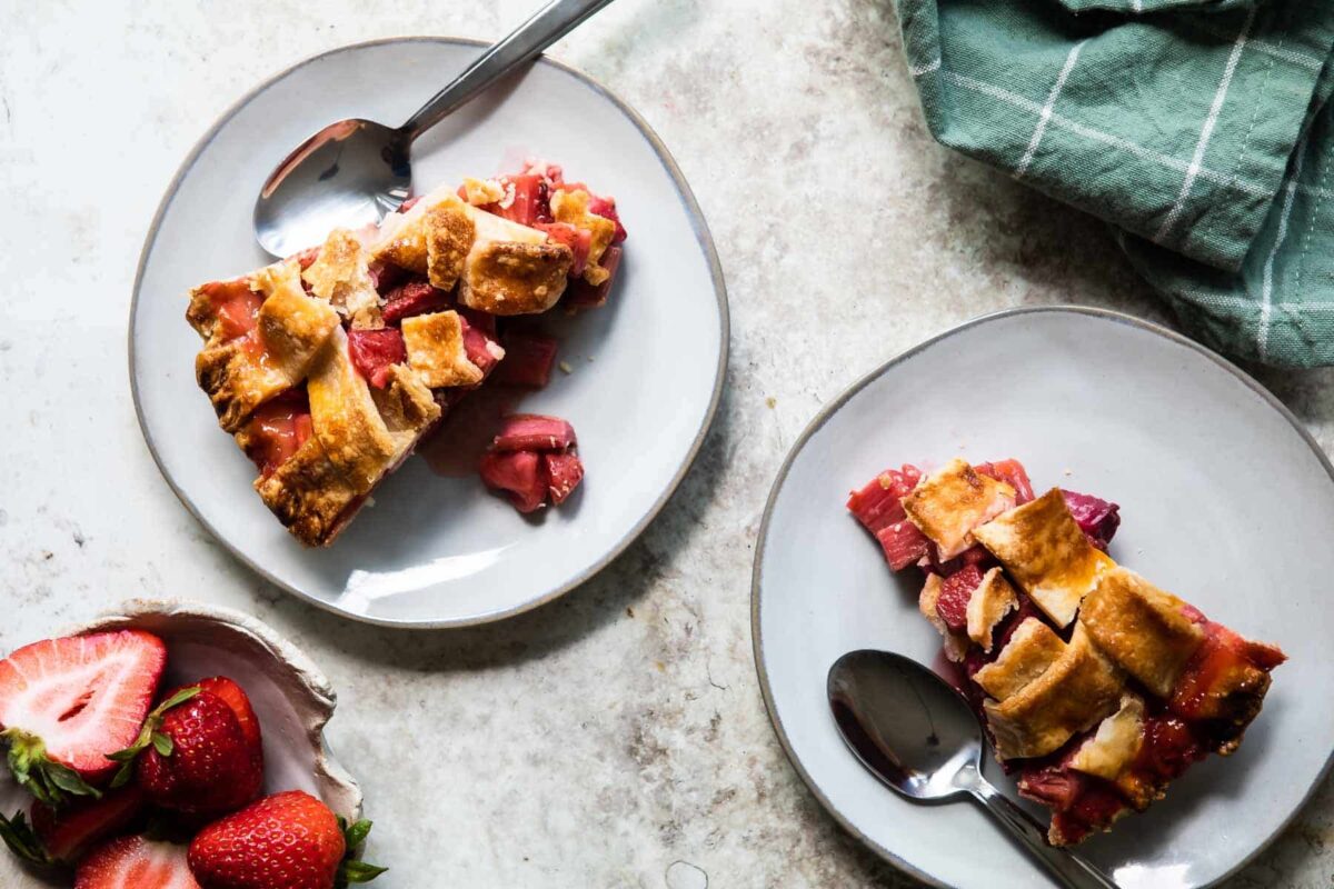 Strawberry rhubarb pie on two white plates.