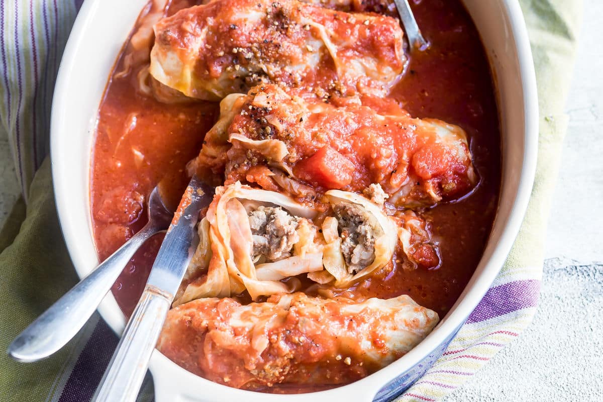 Stuffed cabbage rolls in a white baking dish.