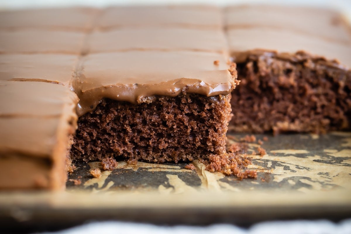 A pan of Texas sheet cake cut into squares and some squares removed from the pan.