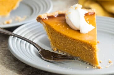 A slice of pumpkin pie on a gray plate.