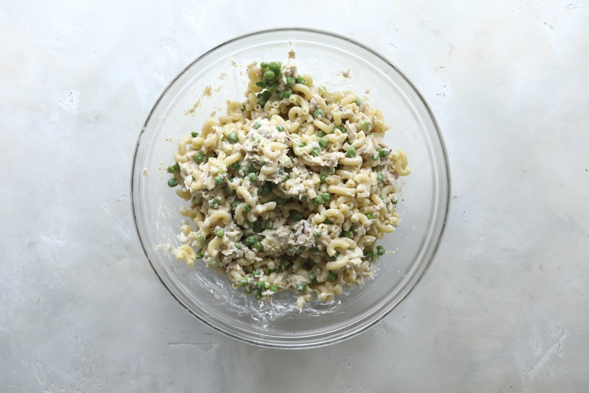 A clear mixing bowl with tuna pasta salad.