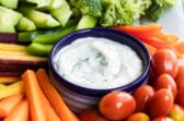 Veggie dip in a small navy blue bowl surrounded by vegetables.