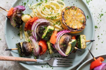 A plate with veggie kabobs and pasta.