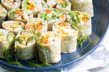 Veggie tortilla roll ups on a blue platter.